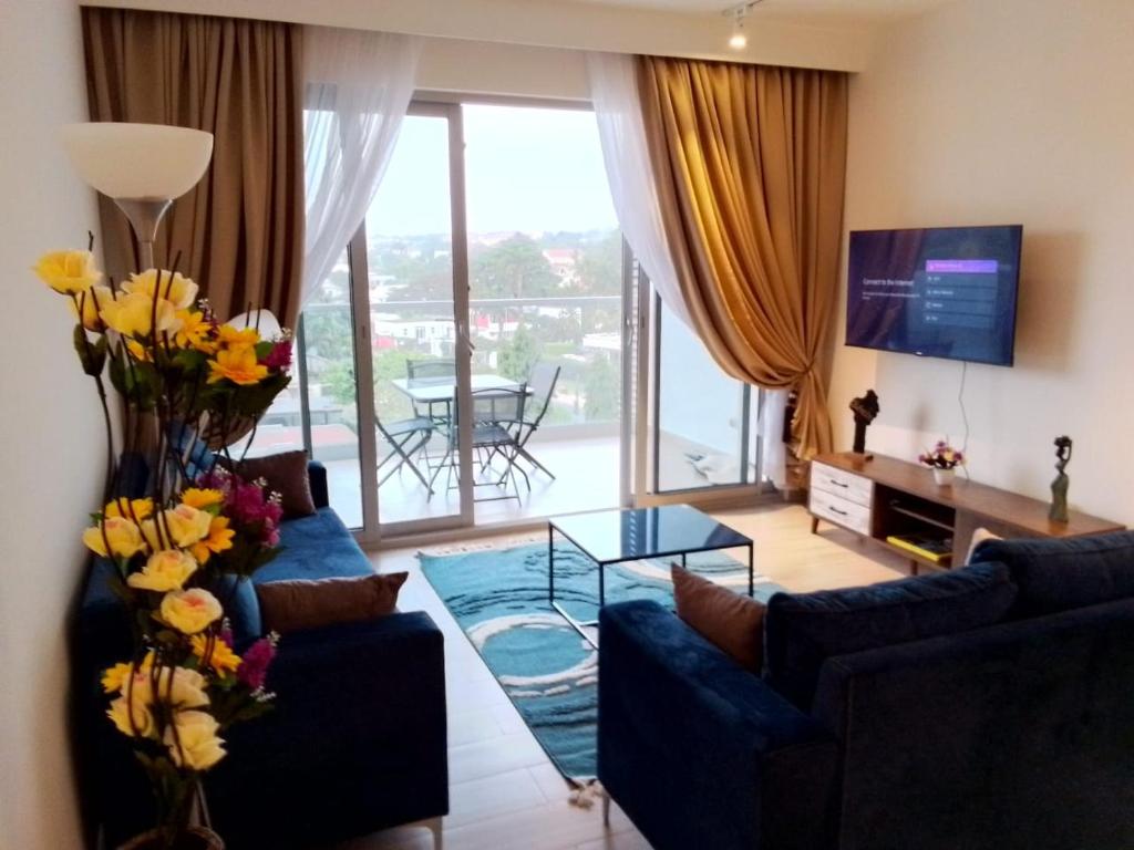 un soggiorno con divano blu e tavolo in vetro di 1 BDR 74SQM Luxury APT with separate Bedroom Pool, Gym, Balcony, King Size Bed Cantonments a Accra