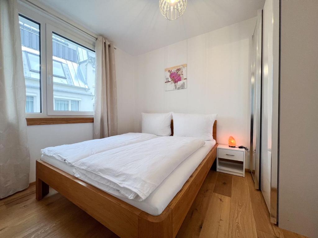 ein Schlafzimmer mit einem großen Bett in einem Zimmer mit einem Fenster in der Unterkunft Modern apartment w/ cozy balcony near city center in Wien