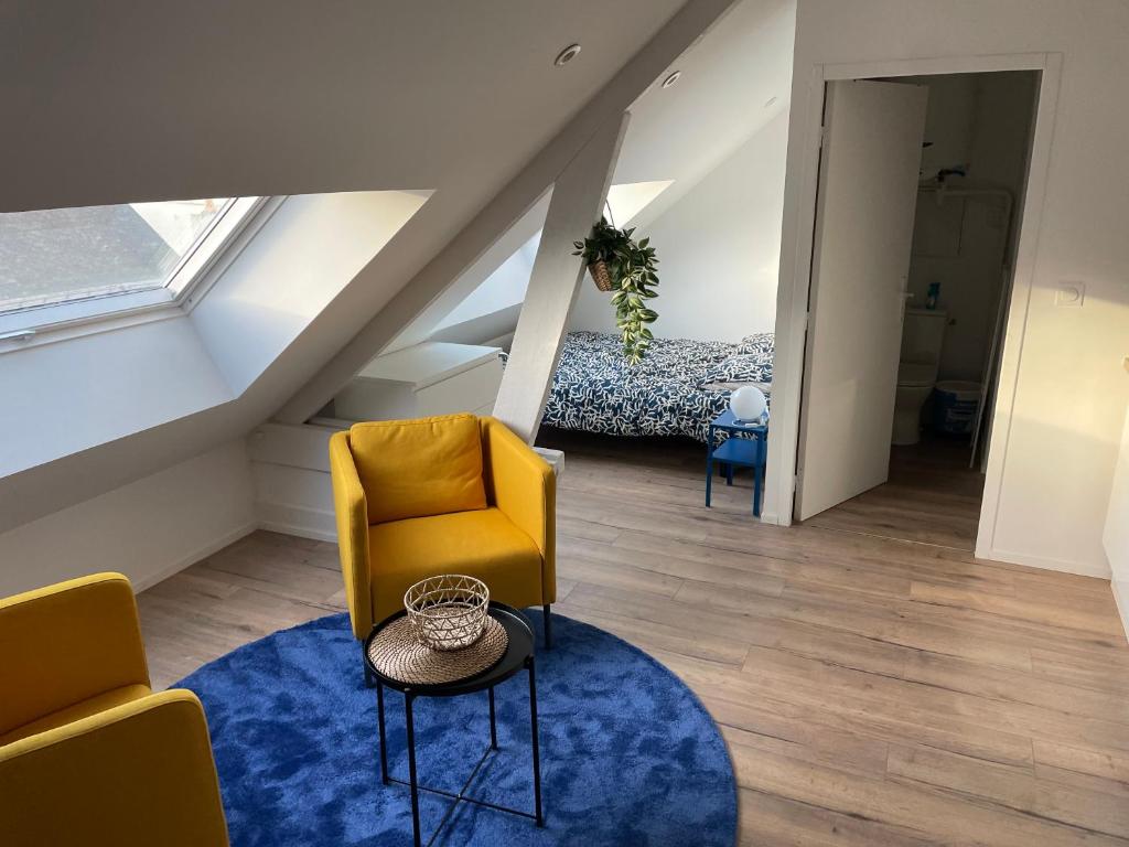 uma sala de estar com uma cadeira amarela e um tapete azul em Studio 303 - Hyper Centre - Intégralement rénové - Toutes commodités à pied em Saint-Nazaire