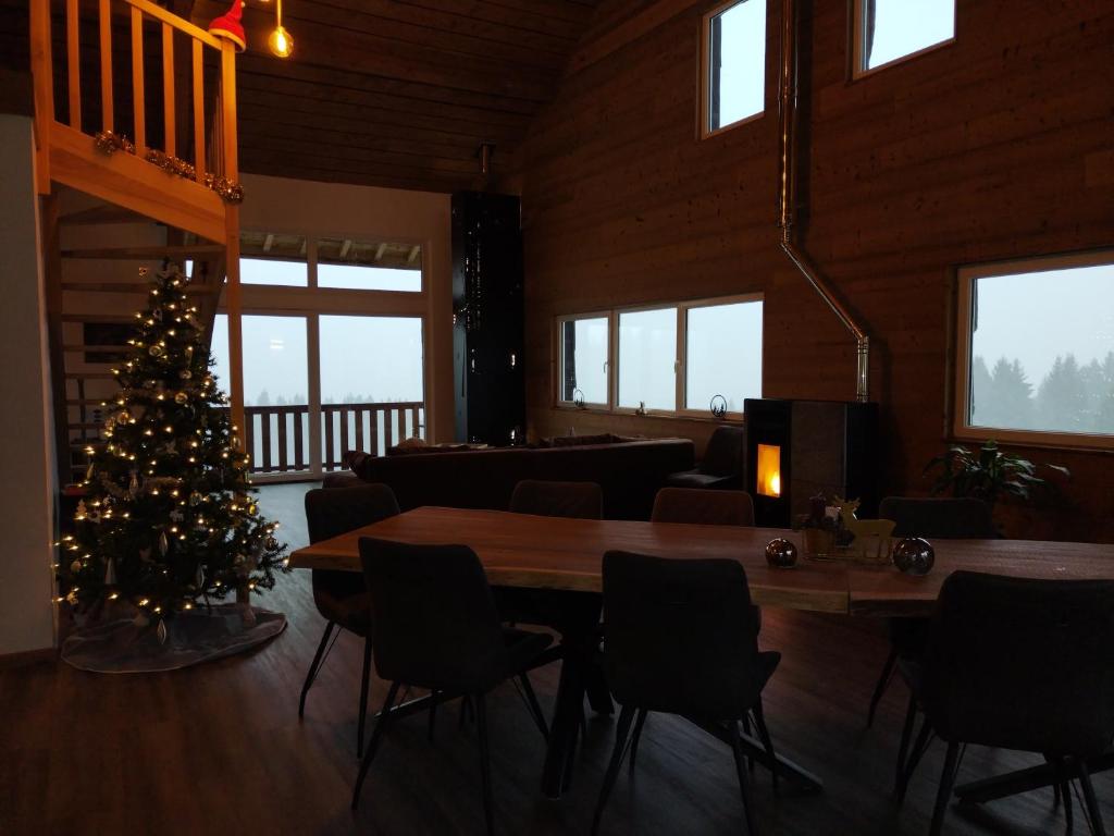 un sapin de Noël dans une pièce avec une table et des chaises dans l'établissement Chambre d'hôtes LES BRIMBELLES, à Gérardmer