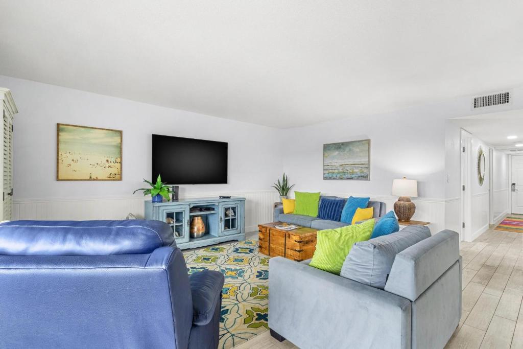 a living room with two couches and a tv at Beach Oasis - Beautifully Remodeled Beachside Condo at Holiday Villas II with Heated Pool! in Clearwater Beach
