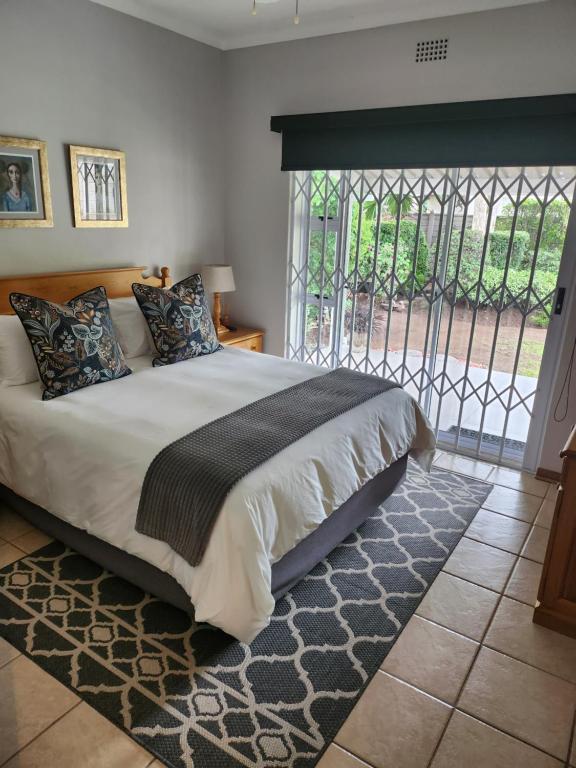 um quarto com uma cama grande e uma janela em Rosewood Guest Cottage em Vryheid