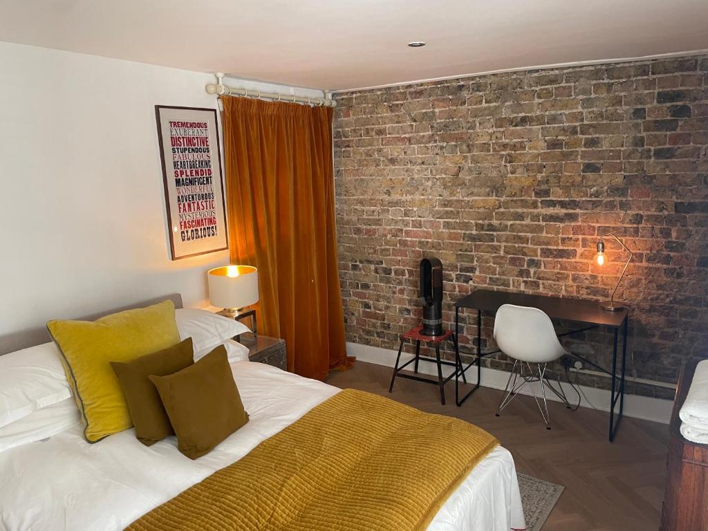 sypialnia z łóżkiem i ceglaną ścianą w obiekcie Beautiful London Victorian house, sleeps 12 w Londynie