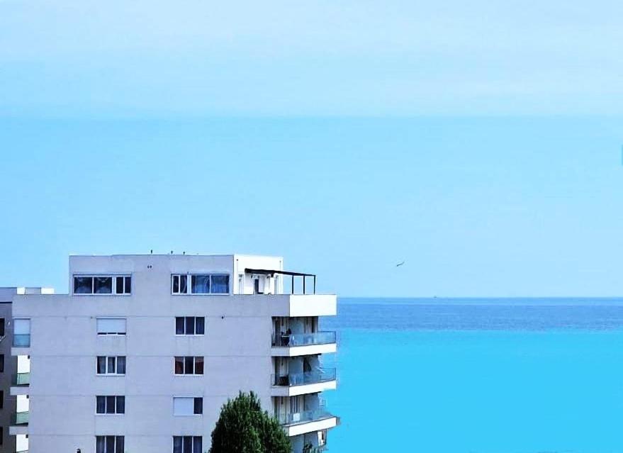 ein weißes Apartmenthaus mit dem Meer im Hintergrund in der Unterkunft FERNWEH No 5 Boutique Hotel MAMAIA Nord in Mamaia Nord – Năvodari