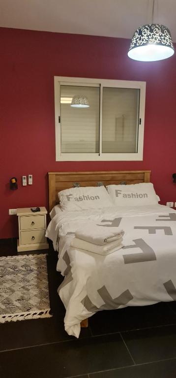 a bedroom with two beds and a red wall at Studio at the Kibbutz in Ashdot Ya‘aqov
