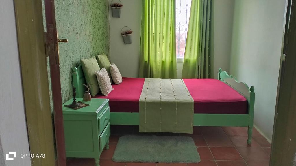 um quarto com uma cama e uma janela com cortinas verdes em Dar el haouaria em El Haouaria
