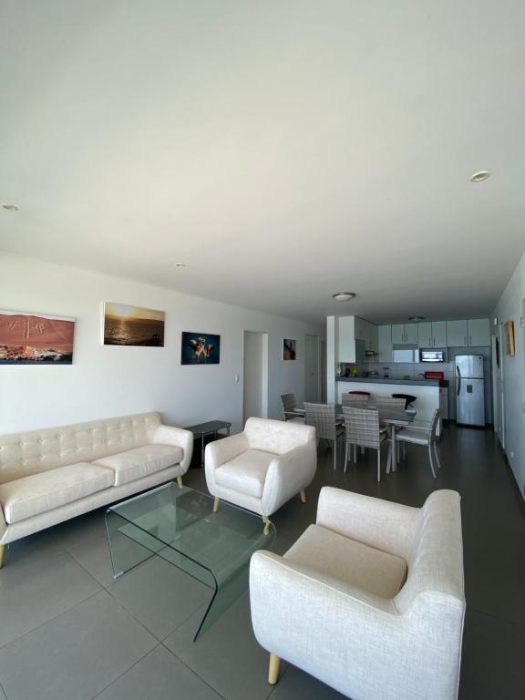 una sala de estar con 2 sofás blancos y una mesa. en Condominio Nuevo Paracas - Sotavento, en Paracas