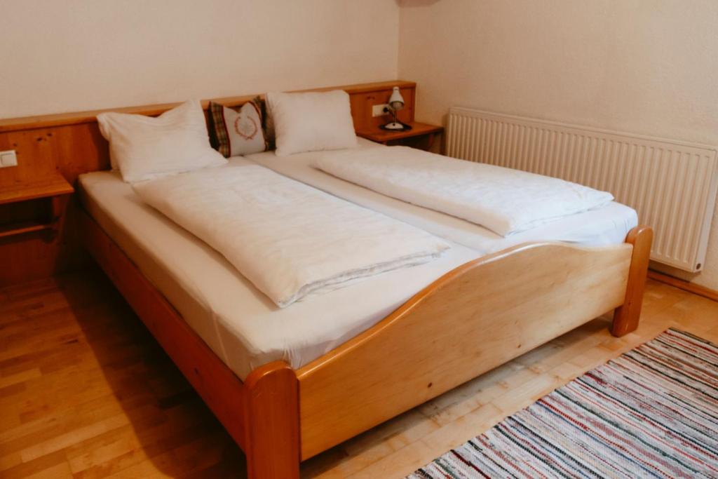 Tofererhof في باد هوفغاستين: سرير خشبي عليه أغطية ووسائد بيضاء