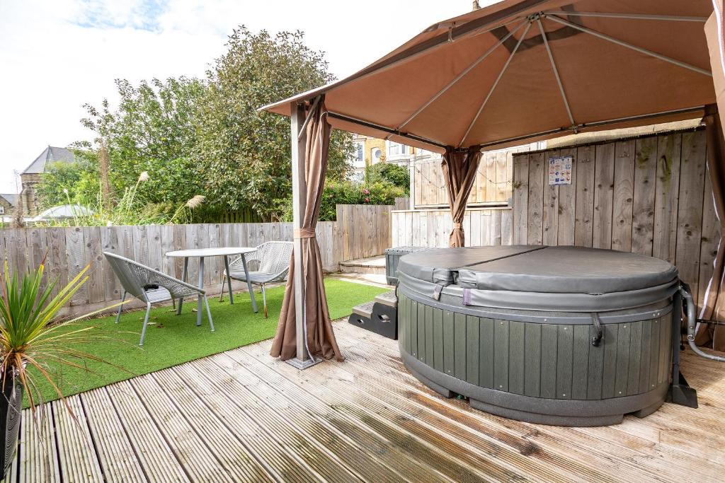 einen Whirlpool und einen Regenschirm auf einer Terrasse in der Unterkunft Seadream Luxury Holiday Home with Hot Tub Sleeps 6 in Scarborough