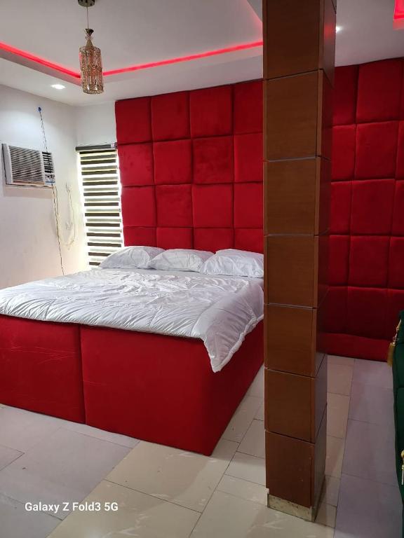 a bedroom with a red headboard and a red wall at O'ffidaus J Luxury Hotel And Suites Int Ltd in Benin City