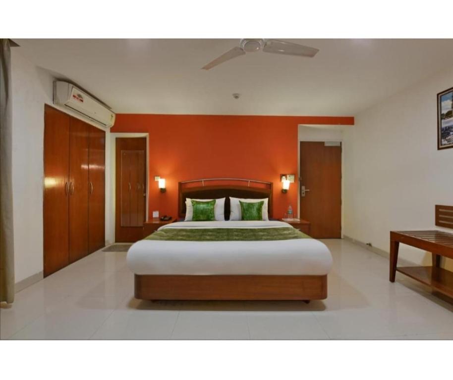 una camera con un grande letto con una parete arancione di Golden Dream a Nuova Delhi