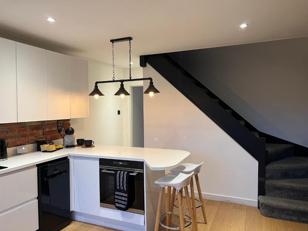 a kitchen with white cabinets and a black staircase at Hempshill Lane holiday home in Nottingham