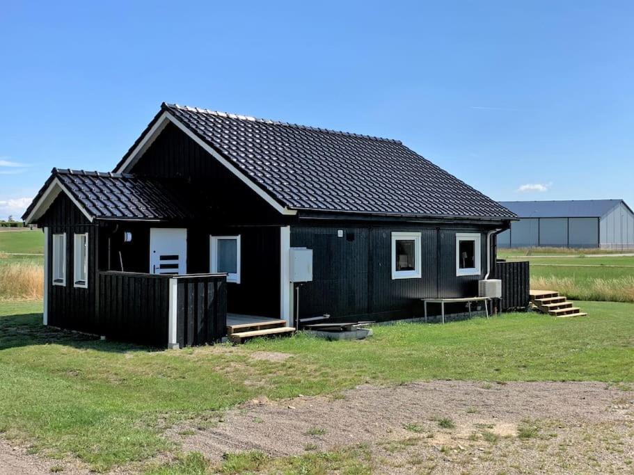 ein schwarzes Haus mit einer Bank auf einem Feld in der Unterkunft Bo bekvämt i eget hus in Ekeby
