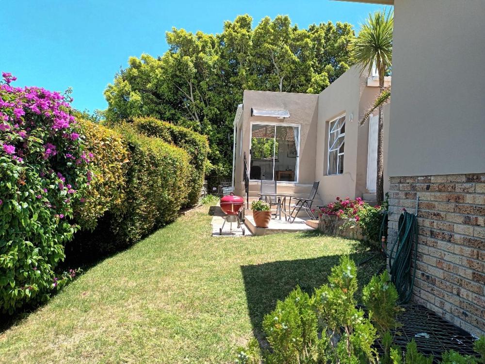 a backyard of a house with a lawn and flowers at Sea Cottage in Hout Bay