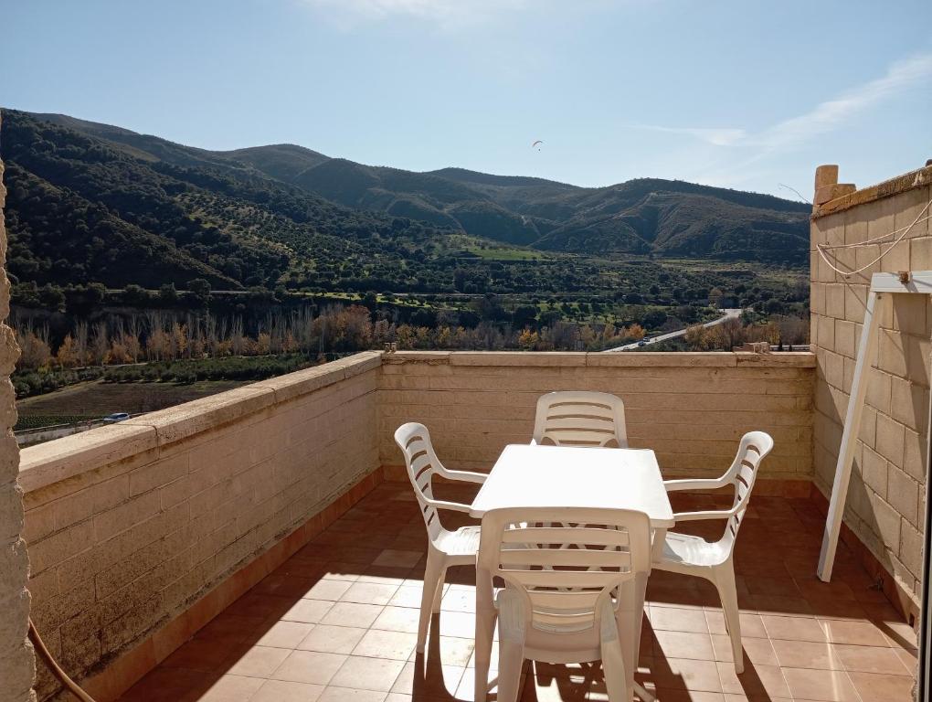 una mesa blanca y sillas en un balcón con montañas en Apartamento Urba Ruta del Veleta, en Cenes de la Vega