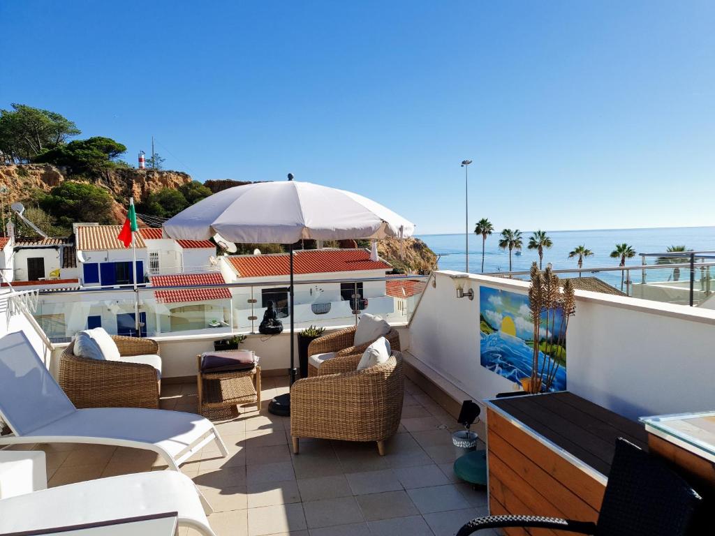 a balcony with chairs and an umbrella and the ocean at Magnifique Duplex avec piscine en bord de mer in Olhos de Água