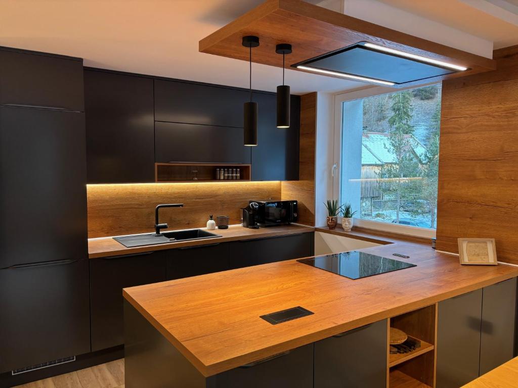 a kitchen with black cabinets and a wooden counter top at Modern apartment Leon in Gozd Martuljek