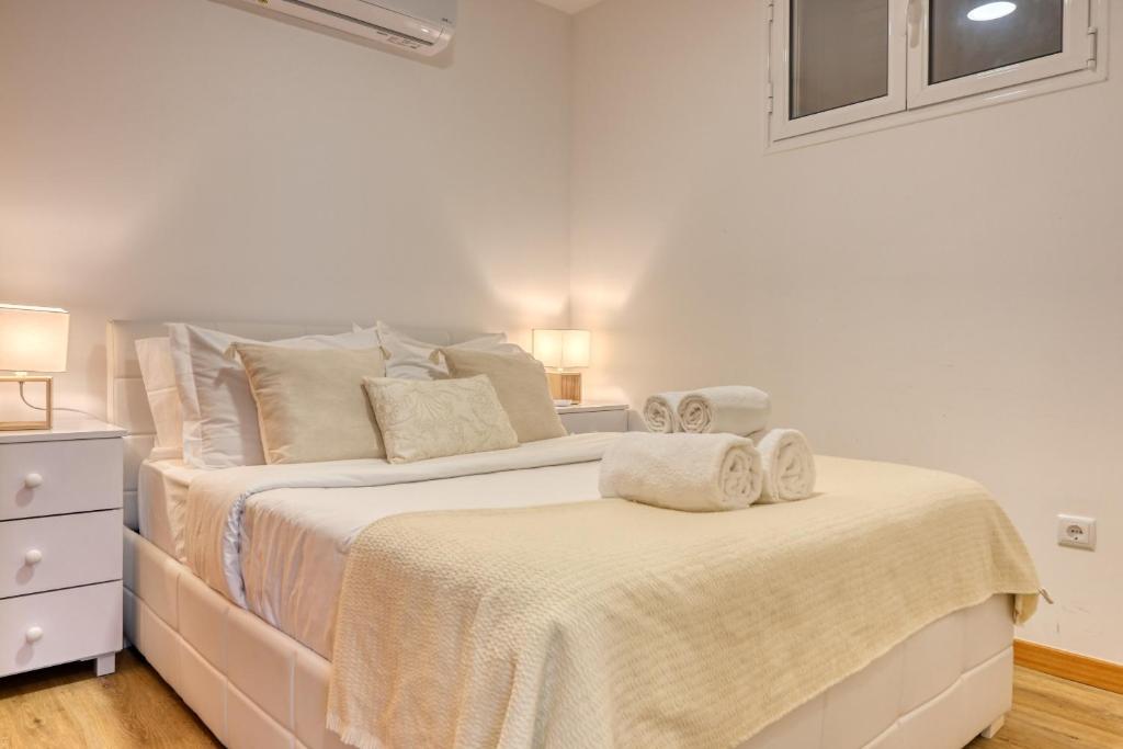 a white bedroom with two beds with towels on them at Casa Familia Pestana 1, a Home in Madeira in Seixal