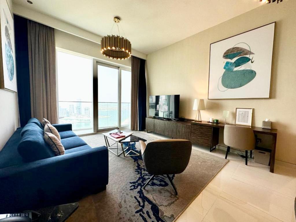a living room with a blue couch and a tv at Myhome Avani Palm View Dubai in Dubai