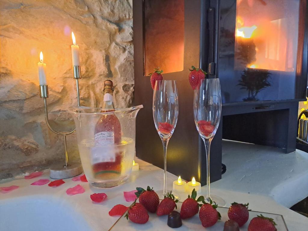 zwei Gläser Wein und Erdbeeren auf einem Tisch mit Kerzen in der Unterkunft Casa Romántica con Sauna privada Eternal Rural in Jimena de la Frontera