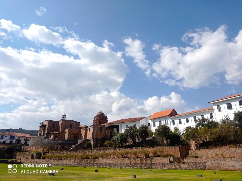 a group of buildings in a field with a cloudy sky at APARTAMENTO URMA Cuzco in Cusco