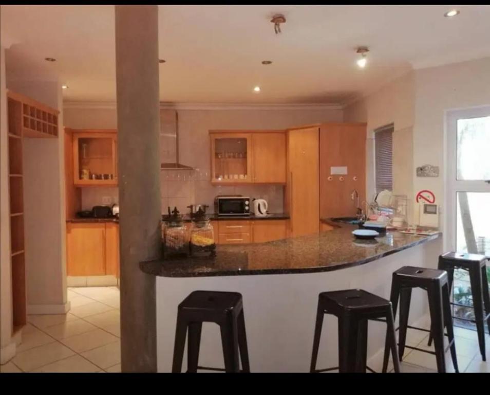 a kitchen with a counter with stools in it at Harbour Close Home in Cape Town