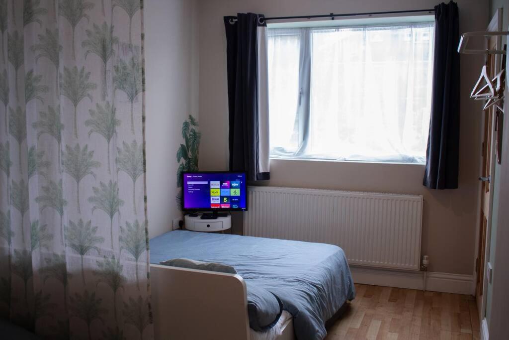 a bedroom with a bed with a television on it at Cosy apartment 7 mins walk from Wembley stadium in London