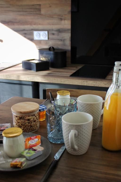 a table with cups and a plate of food and orange juice at Gîte spa la parenthèse in Sauve
