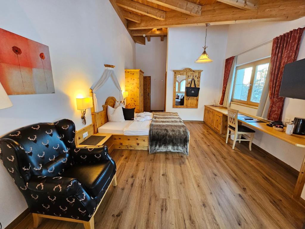 a living room with a couch and a bed and a desk at Chasa Castello relax & spa in Samnaun