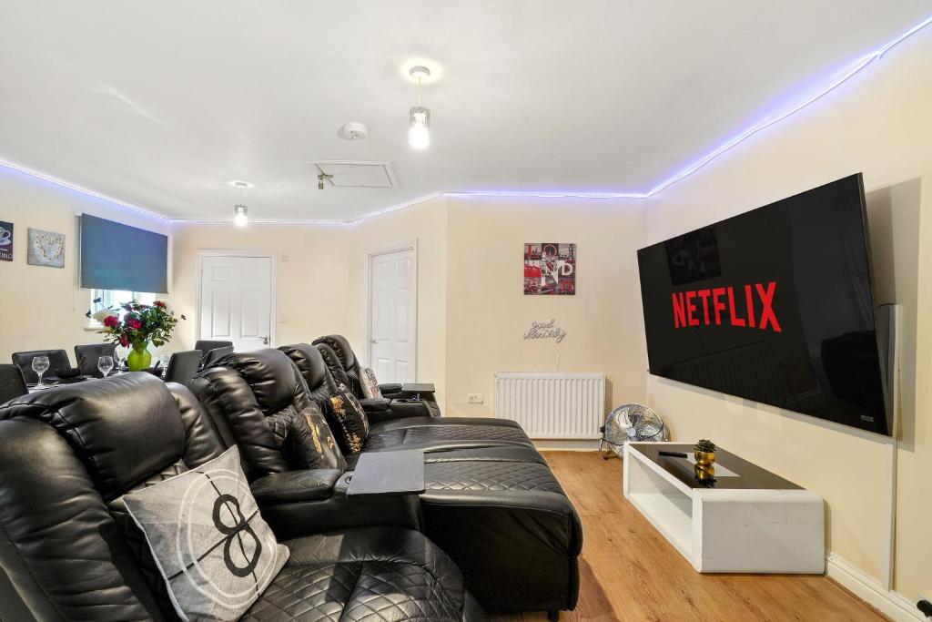 a living room with a black leather couch and a television at Lt Properties Unique Bungalow style Spacious one bedroom Apartment in Luton Town centre super size round bed Netflix in Luton