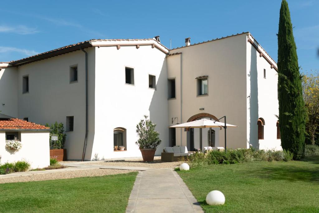 un grand bâtiment blanc avec une pelouse devant lui dans l'établissement Casale La Gora - B&B di charme, à Figline Valdarno