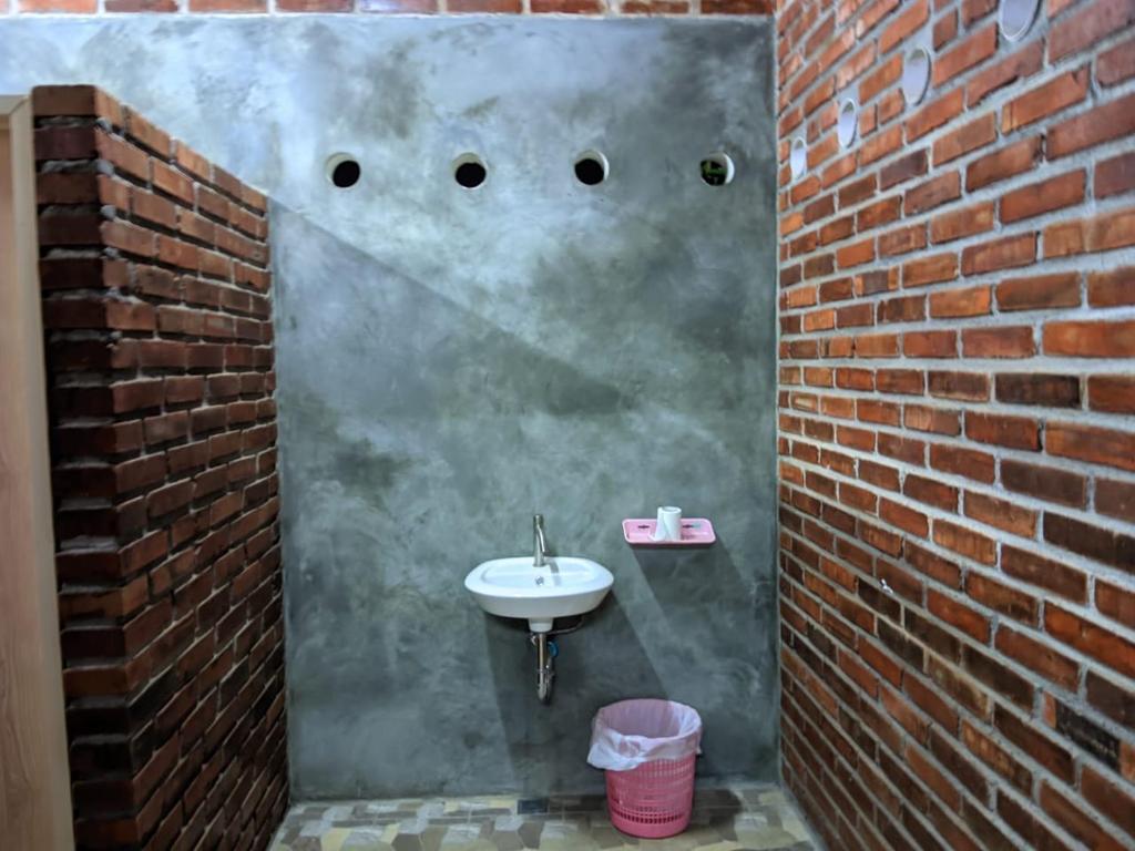 een badkamer met een wastafel en een bakstenen muur bij Omah Mbah Manten in Tuntang