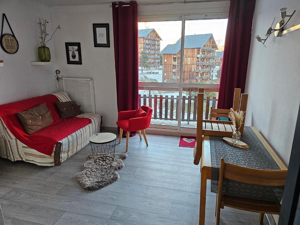 - un salon avec un canapé rouge et une grande fenêtre dans l'établissement Residence bois d'aurouze pied des pistes, à Saint-Étienne-en-Dévoluy