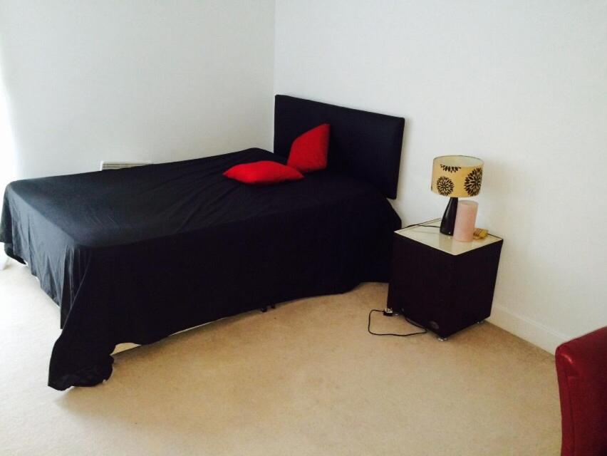 a bedroom with a black bed with red pillows at EXCEL STUNNING DUPLEX PENTHOUSE in London