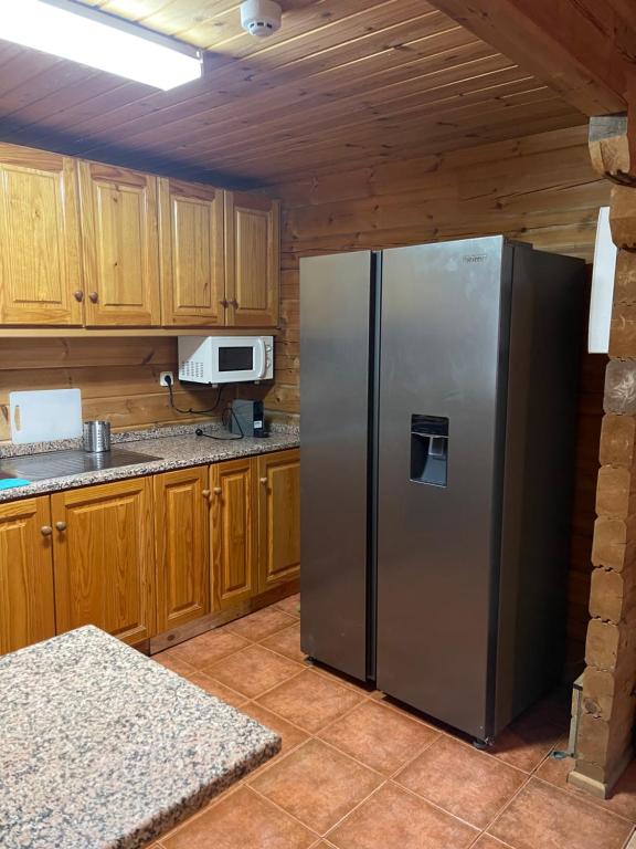 a stainless steel refrigerator in a kitchen with wooden cabinets at Chalé do Sossego Serra da Estrela in Cortes do Meio