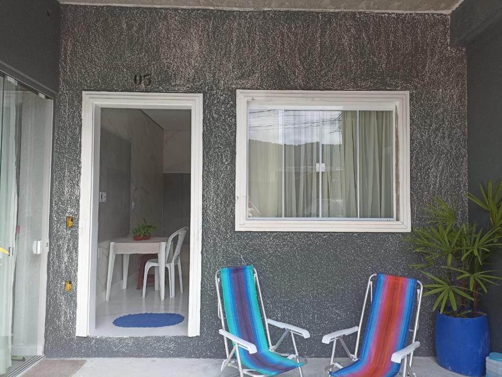 two chairs sitting outside of a house with a table at Winter X locações 03 in Itapema