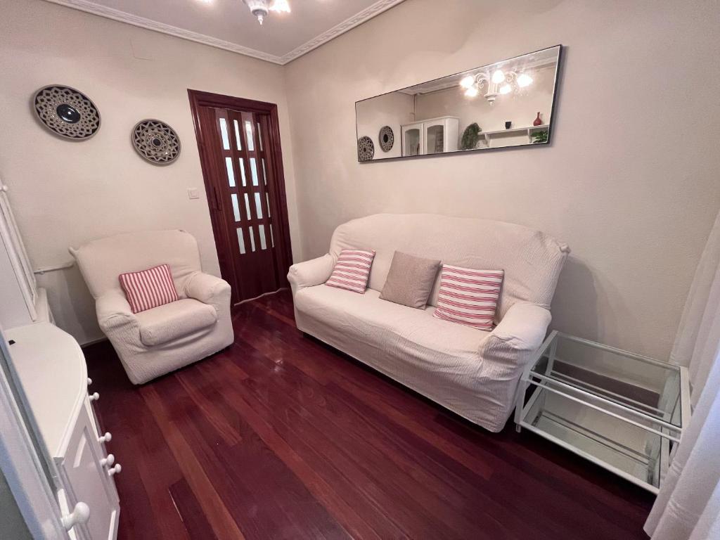 Apartamento La Luz de Reinosa 3 في رينوسا: غرفة معيشة مع كرسيين بيض ومرآة