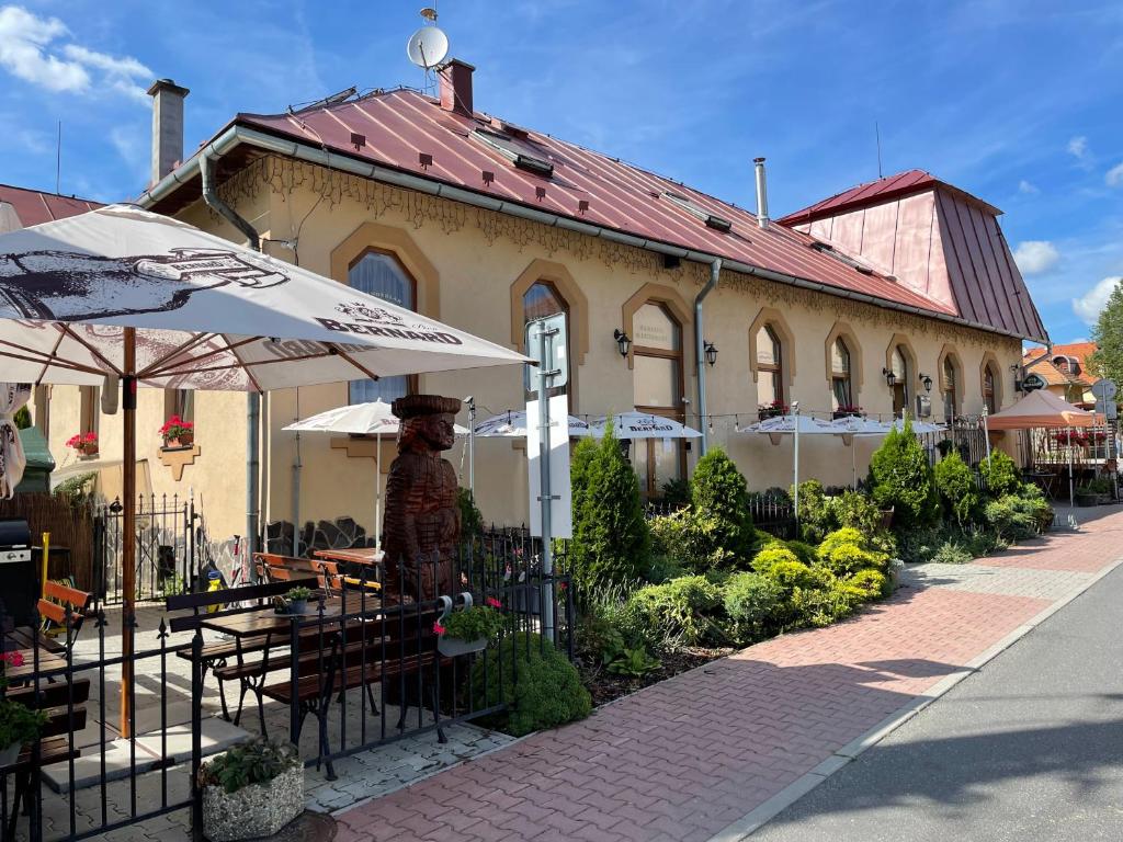 a building with an umbrella and a table and chairs at Penzion Manderlak in Liptovský Mikuláš