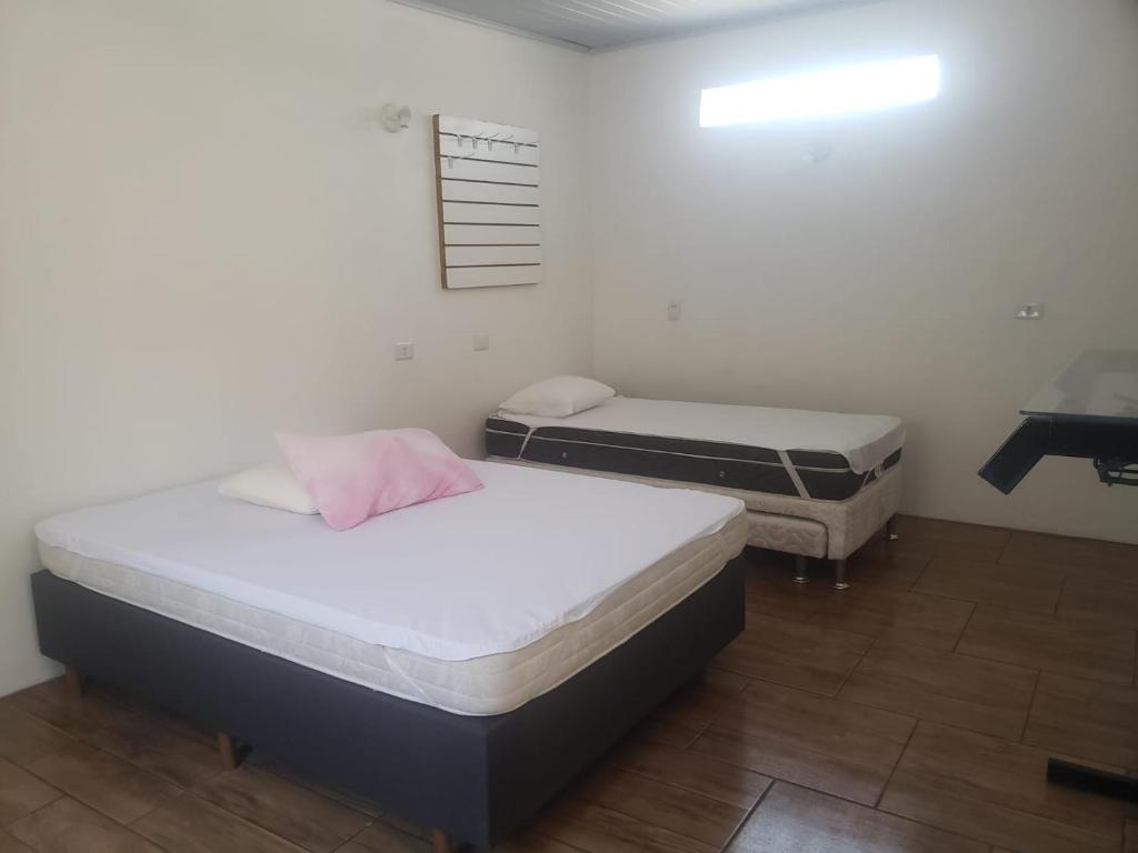 two beds in a room with a sink and a desk at Apartamentos de Verão in Tramandaí