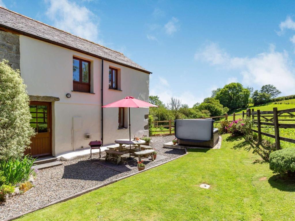 a garden with a table and an umbrella and a tv at 2 Bed in Fowey LTBUZ in Cardinham