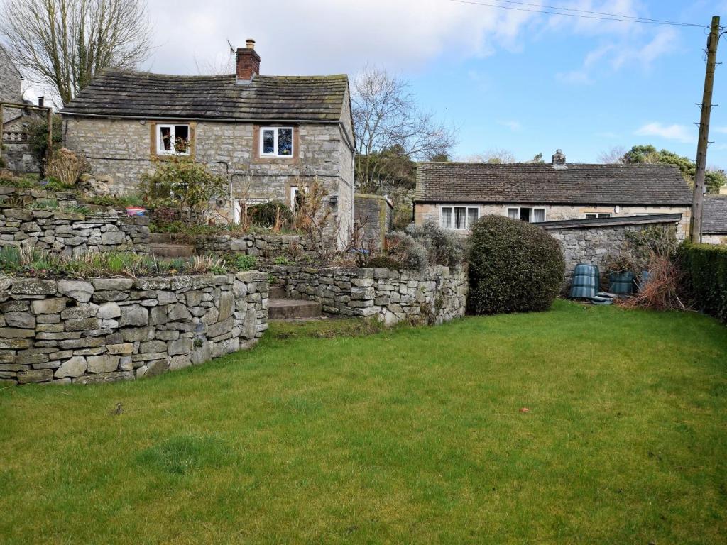 an old stone house with a stone wall and a yard at 2 Bed in Ashford in the Water PK932 in Great Longstone