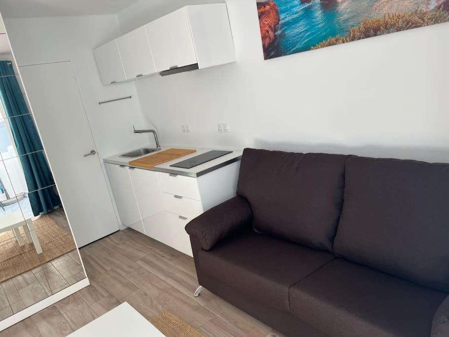 ein Wohnzimmer mit Couch und Küche in der Unterkunft 26 Puerto del Carmen Palm tree in Puerto del Carmen