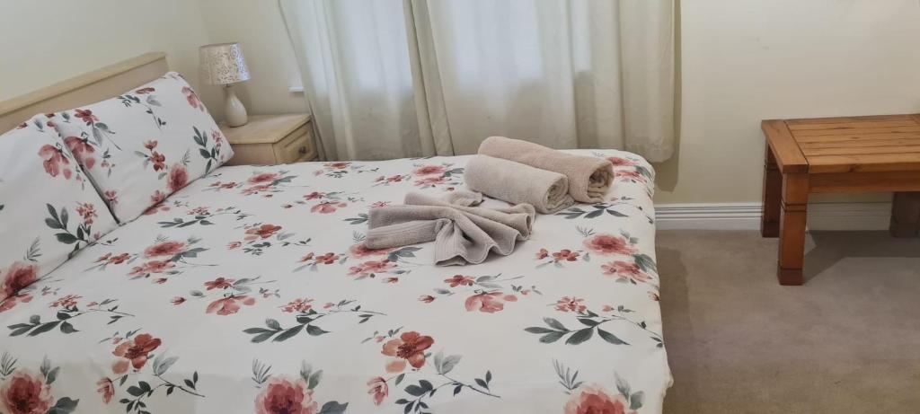 uma cama com uma colcha floral e toalhas em 2 bed cosy apartment in heart of Mullingar. em Mullingar