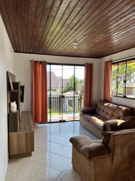 Una sala de estar con un sofá y una ventana grande. en Casa no centro de Garopaba, en Garopaba