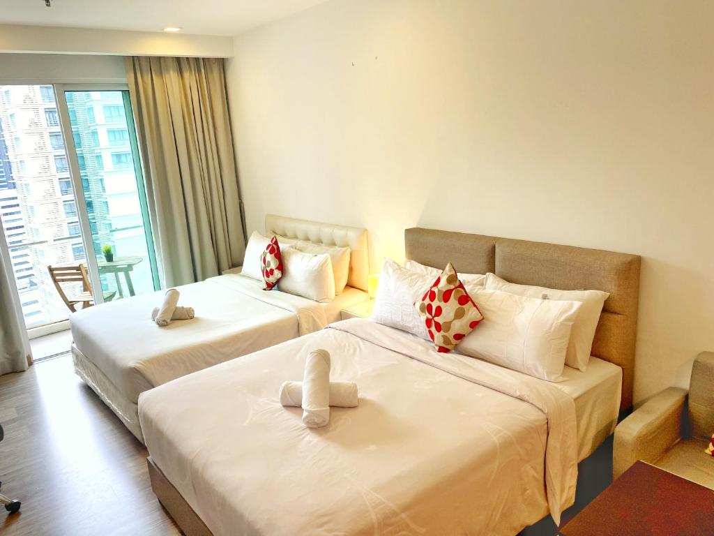 a hotel room with two beds and a couch at LILA SUITES ONE BUKIT CEYLON in Kuala Lumpur