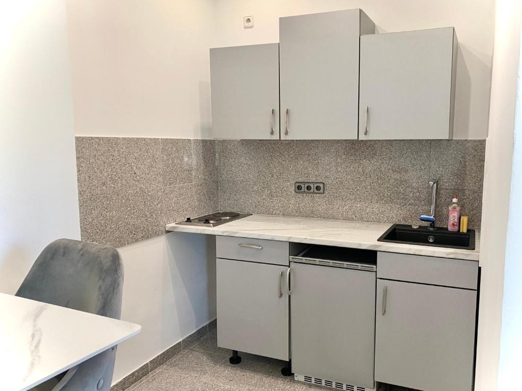 a small kitchen with white cabinets and a sink at kleines Apartment, nähe Stadtzentrum im 1ten Obergeschoss in Bamberg