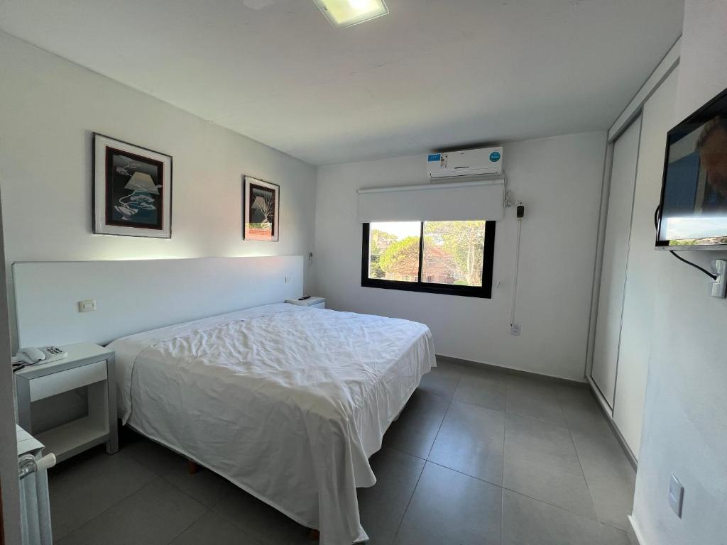 Un dormitorio blanco con una cama y una ventana. en Tres Estrellas y Un Sol Departamentos, en Valeria del Mar
