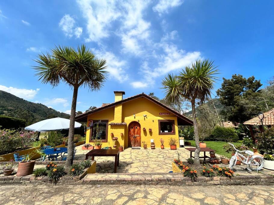 a yellow house with palm trees in front of it at Casa de eventos y descanso in La Calera