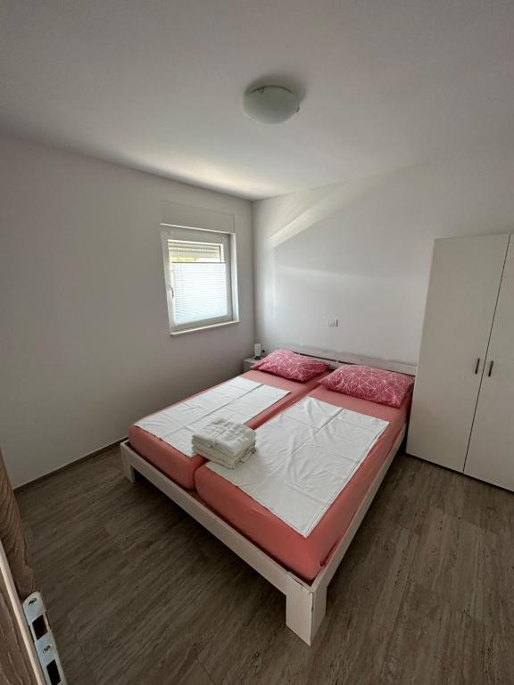 a bedroom with a bed with red and white sheets at Apartmani Tamaris in Murter