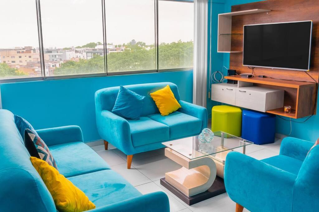 sala de estar azul con sillas azules y TV en departamento moderno en surco., en Lima